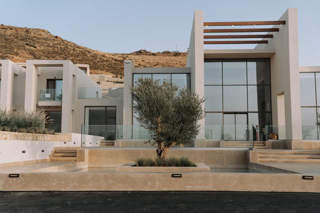 Stunning modern villa with glass facade and unique olive tree landscape.